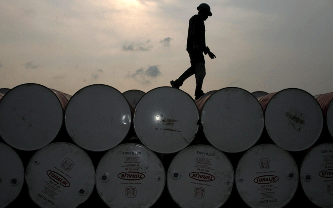 Imagen de un trabajador caminando sobre barriles de petróleo