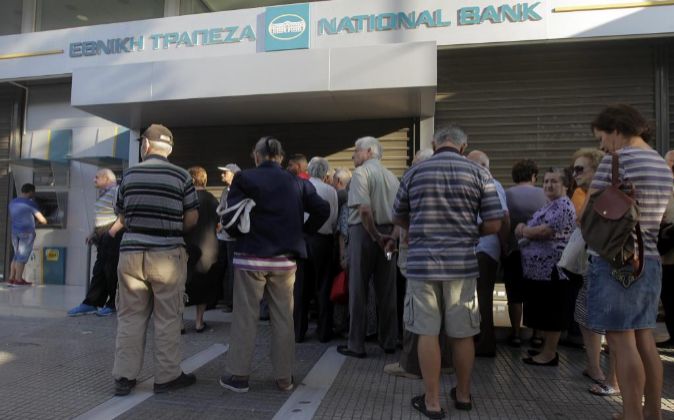 Ciudadanos griegos hacen cola ante el cajero de un banco cerrado.