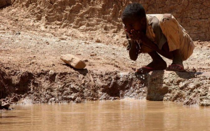 Un niño somalí bebe agua en una presa construida por el hombre en el...
