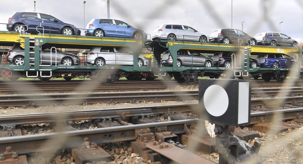 Un tren con vehículos nuevos de Volkswagen delante de una planta de...