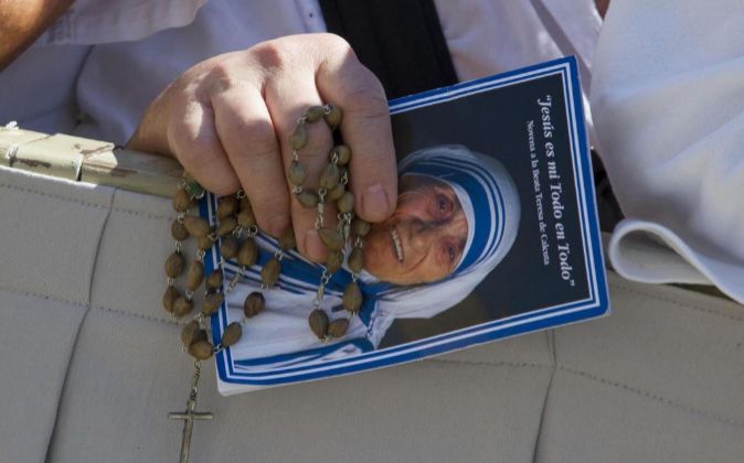 Un hombre sostiene un rosario y una imagen de la Madre Teresa de...