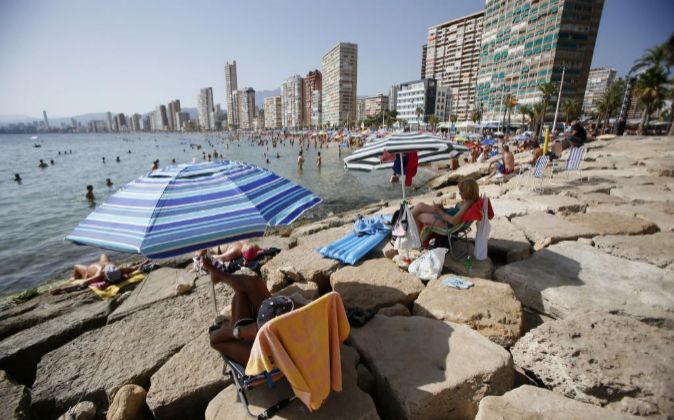 Miles de turistas disfrutan del sol y el agua en la playa de Levante...