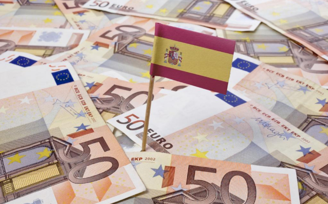 Imagen de una bandera de España sobre billetes de 50 euros