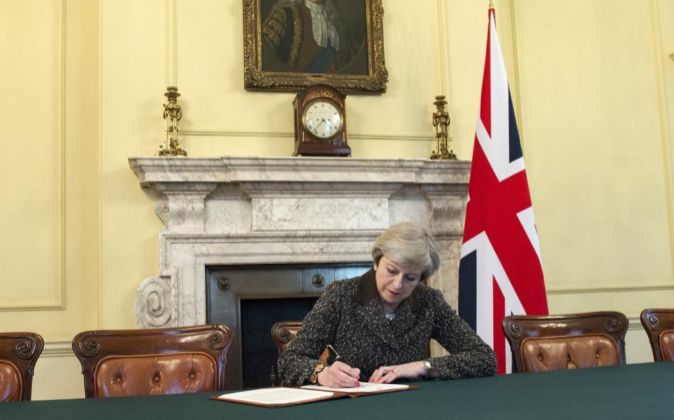 La primera ministra británica, Theresa May, firma la carta en la que...
