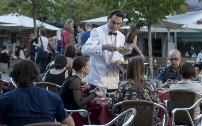 Un camarero atiende a unos clientes en una terraza en Madrid.