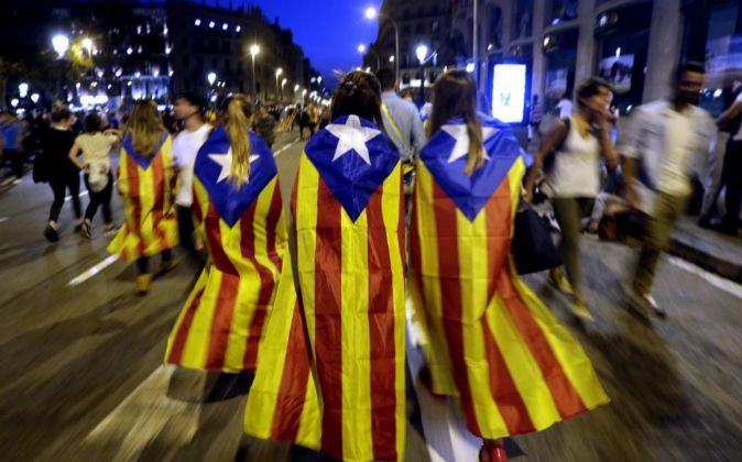 Varias jóvenes con banderas esteladas caminan por plaza de Catalunya.