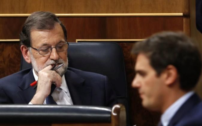 El presidente del Gobierno, Mariano Rajoy (i), escucha una...