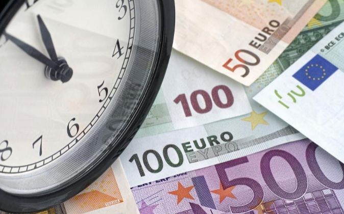 Imagen de un reloj y billetes de euro