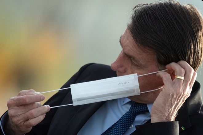El presidente de Brasil, Jair Bolsonaro, se pone una mascarilla...