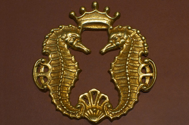 Logo de Grassy, dos caballitos entrelazados bajo una corona. 