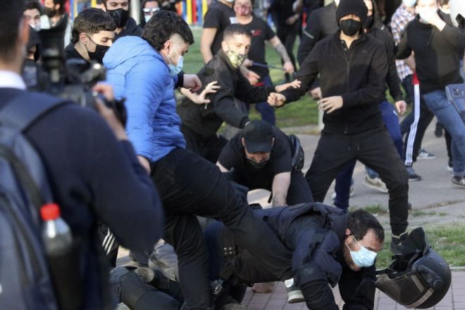 Algunos de los autodenominados antifascistas agreden a uno de los policías nacionales que trataban de proteger al acto de precampaña de Vox en el barrio madrileño de Vallecas, este miércoles.