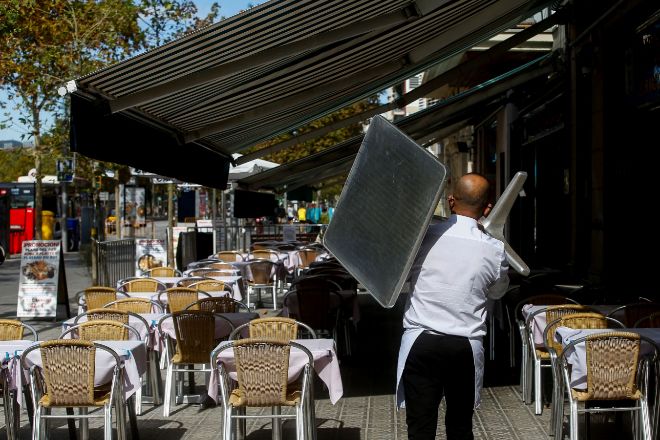 Un camarero recoge una mesa en un restaurante de la Barceloneta en plenas restricciones a la restauración.