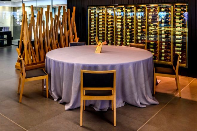 Una de las mesas de Ambivium situada frente a una mnima muestra de las 4.000 botellas que tiene la bodega del restaurante.