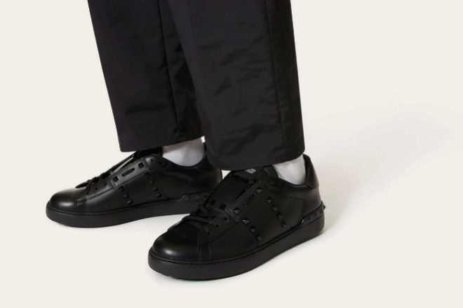 Zapatillas de Valentino en color negro, combinadas con pantaln negro chino y calcetines blancos.