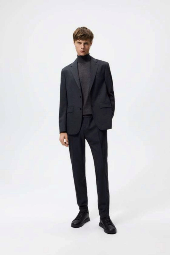 Zapatillas negras minimalistas de Zara combinadas con un traje de color oscuro.