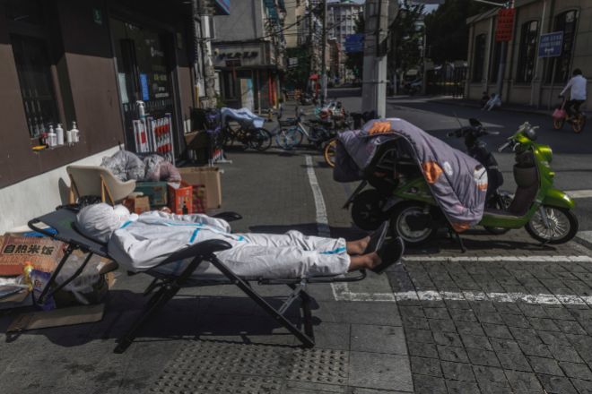 Un repartidor con equipo de protección duerme la siesta en la calle el pasado lunes en Shanghái.