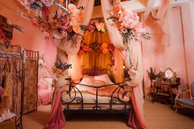El dormitorio cuenta con una romántica cama llena de cojines de seda y rodeada de tules y flores de gasa que forman un soberbio dosel.