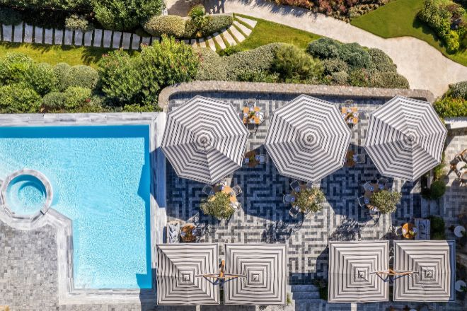 La gama de textiles de Tuuci permite coordinar las sombrillas con el espacio como en el caso de la terraza junto a la piscina del hotel Santa Marina de Mykonos.