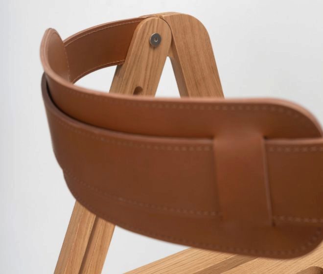 Respaldo de cuero cosido a mano y que adems es la pieza que permite llevar la silla al hombro.