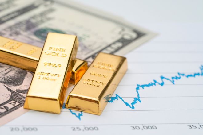 Lingotes de oro sobre cotizaciones y billetes de dólar