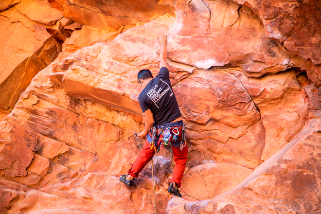 Un escalador asciende por una pared natural de roca.