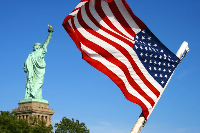 Bandera de EEUU junto a uno de los símbolos del país, la estatua de la libertad.