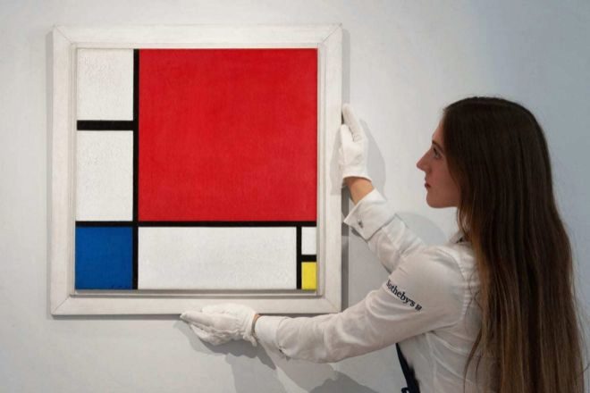 Una empleada de Sothebys coloca el cuadro de Mondrian subastado.
