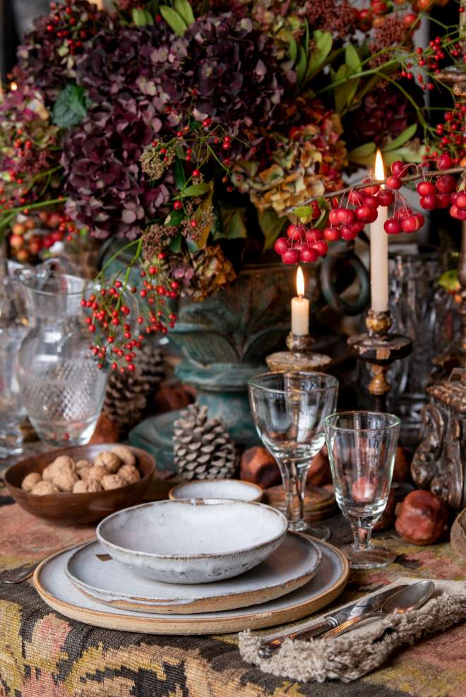 Propuesta de mesa navidea de Toni Espuch con aires rsticos: una alfombra Karabach anudada a mano hace de mantel sobre el que dispone la vajilla de arcilla, servilletas de lino, candelabros de madera y arreglos florales en tonos rojos.