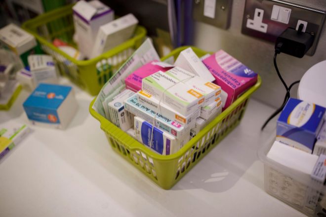 Paquetes de medicamentos con receta en una cesta a la espera de ser revisados y dispensados por un farmacéutico.