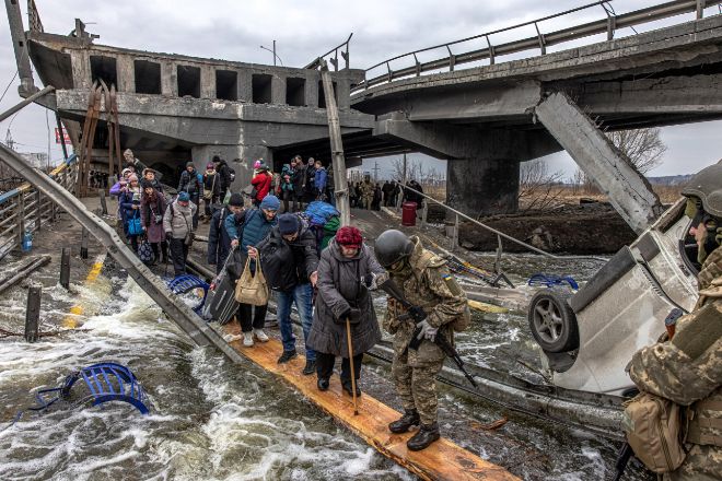 Varias personas cruzan un puente destruido en su huida del frente de batalla en Irpin, Ucrania.
