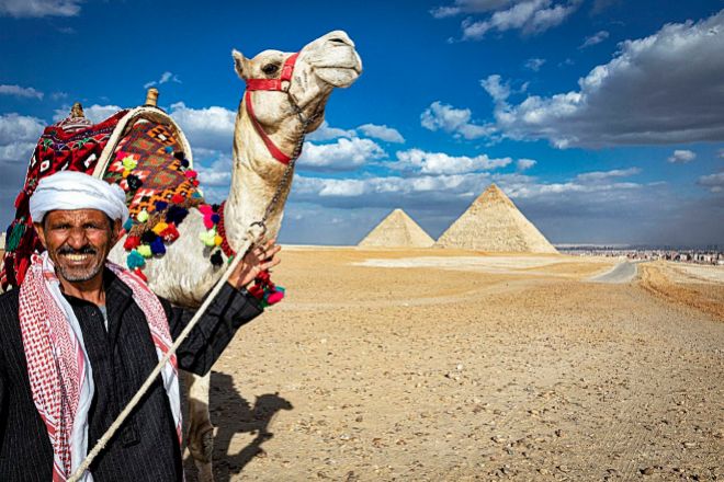 Un camellero ofrece su animal para paseos turísticos. Al fondo, dos de las pirámides de Giza, situadas a unos 20 kilómetros de El Cairo.