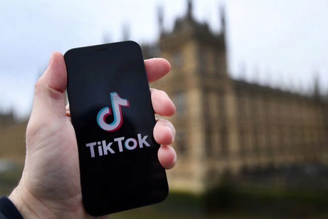 Un móvil con el logotipo de TikTok frente a la sede del Parlamento británico.