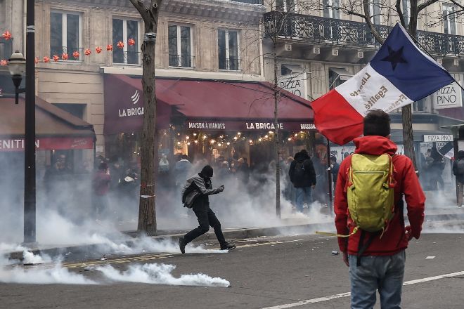 Un manifestante lanza una bomba lacrimógena ayer durante los enfrentamientos con la policía antidisturbios, durante una protesta contra la reforma de las pensiones del gobierno en París.