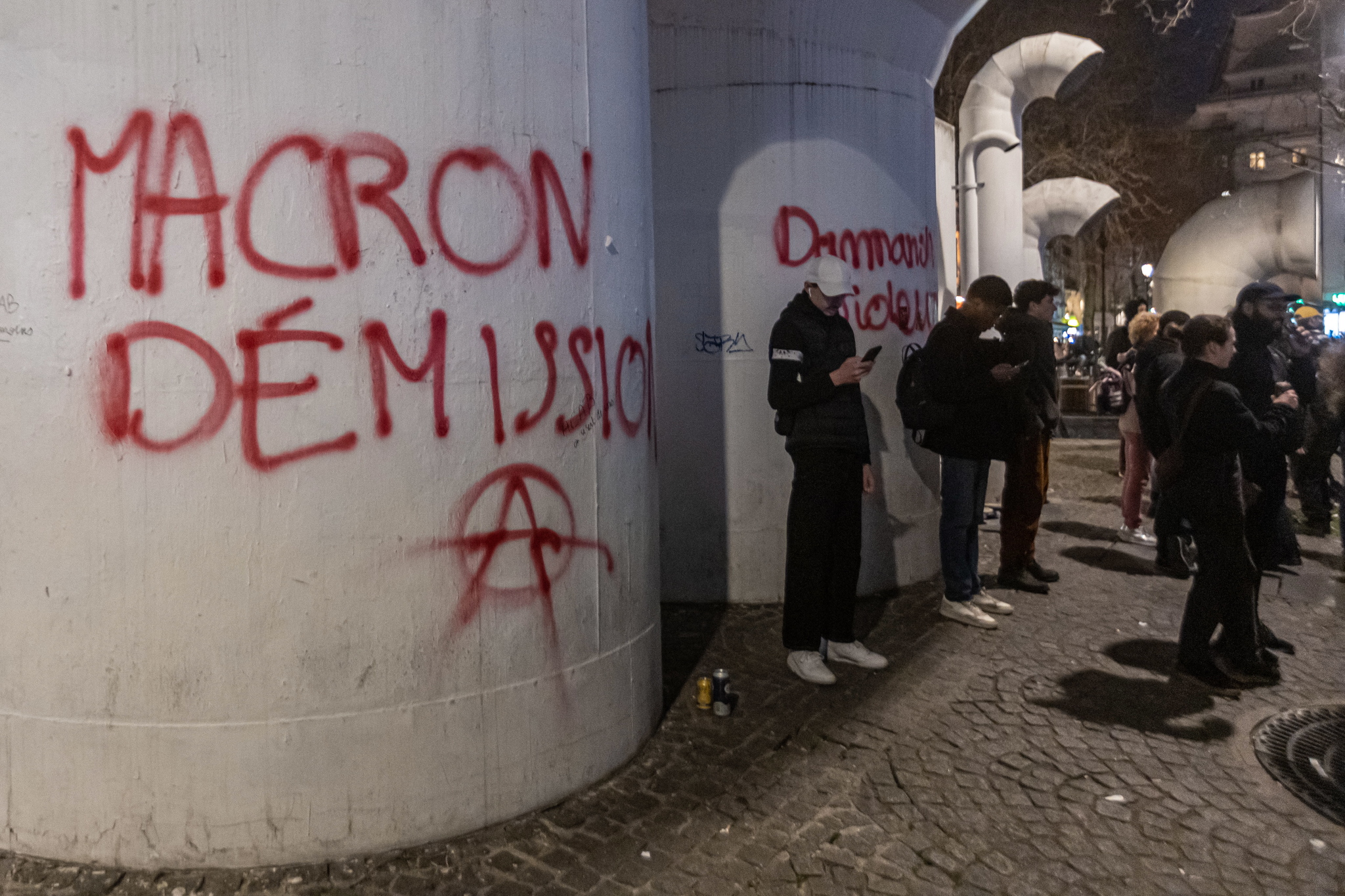 Manifestantes junto a un graffiti que dice "Macron dimisión" en París.