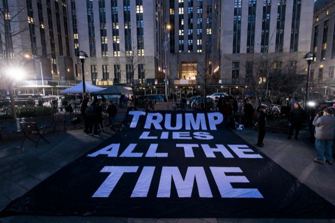La gente despliega hoy un cartel en el que se lee en inglés "Trump miente todo el tiempo" al otro lado de la calle del edificio de la Corte Penal de Nueva York, poco después de la acusación contra el ex presidente Donald J. Tump.