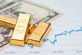 Lingotes de oro sobre billetes de dólares y cotizaciones