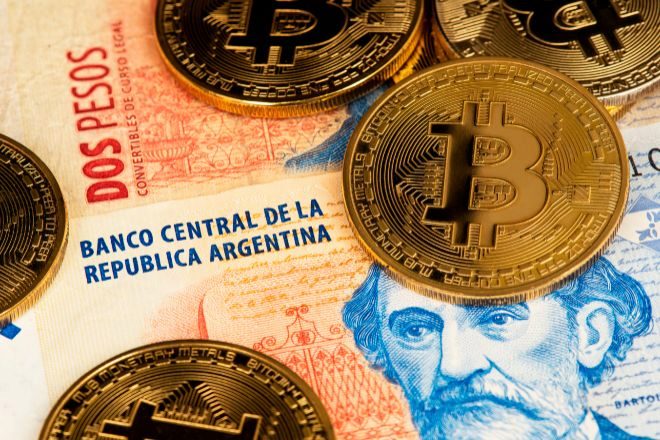 Monedas de bitcoin sobre billetes de pesos argentinos