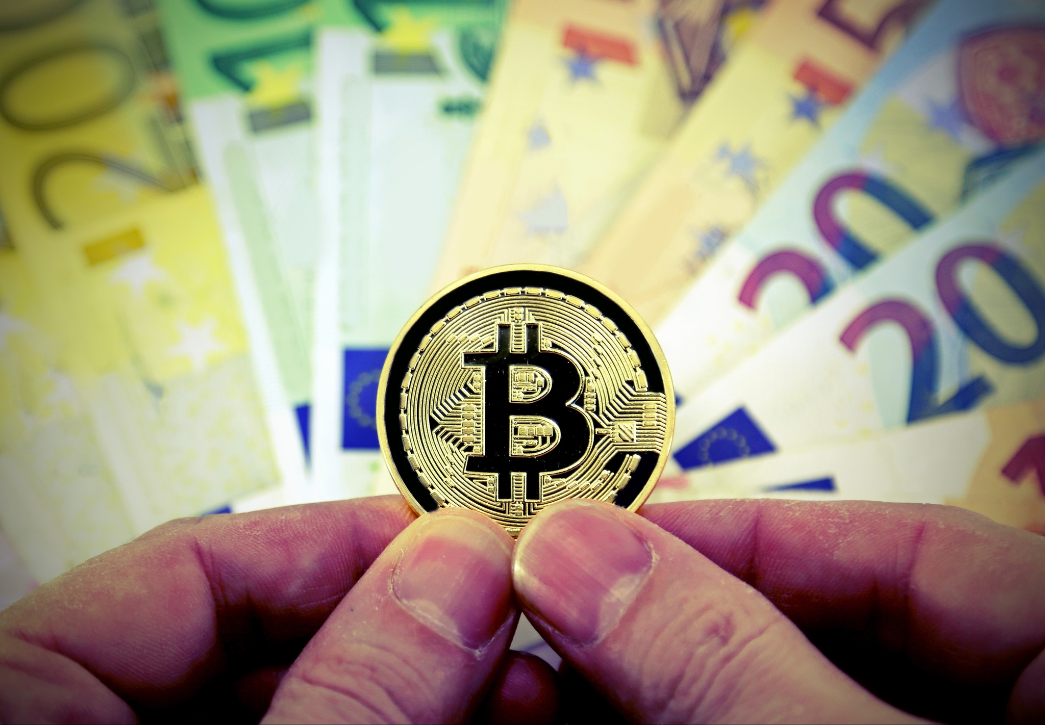 Moneda del bitcoin con billetes de euro