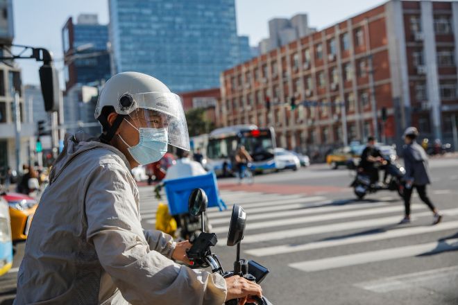 Un hombre con mascarilla en una <em>scooter</em> ayer en Pekín, China, donde la subvariante EG.5 está causando un pico de infecciones este verano.