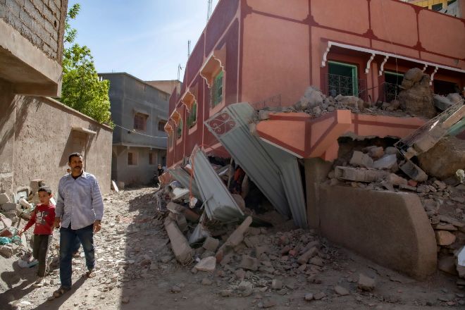 Una persona con un niño camina junto a un edificio dañado tras un terremoto en Marrakech.