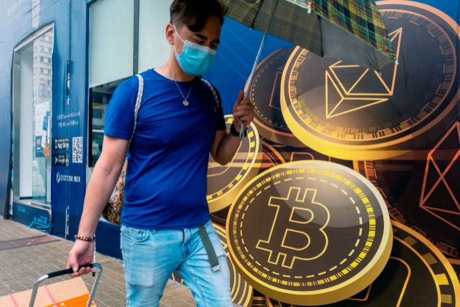 Imagen de un peatón en Asia ante los logos de bitcoin y ethereum