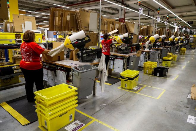 Varios operarios trabajan en la nave de distribución de Amazon.