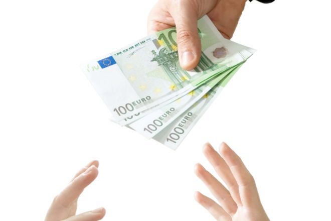 Mano de ejecutivo repartiendo billetes de cien euros.