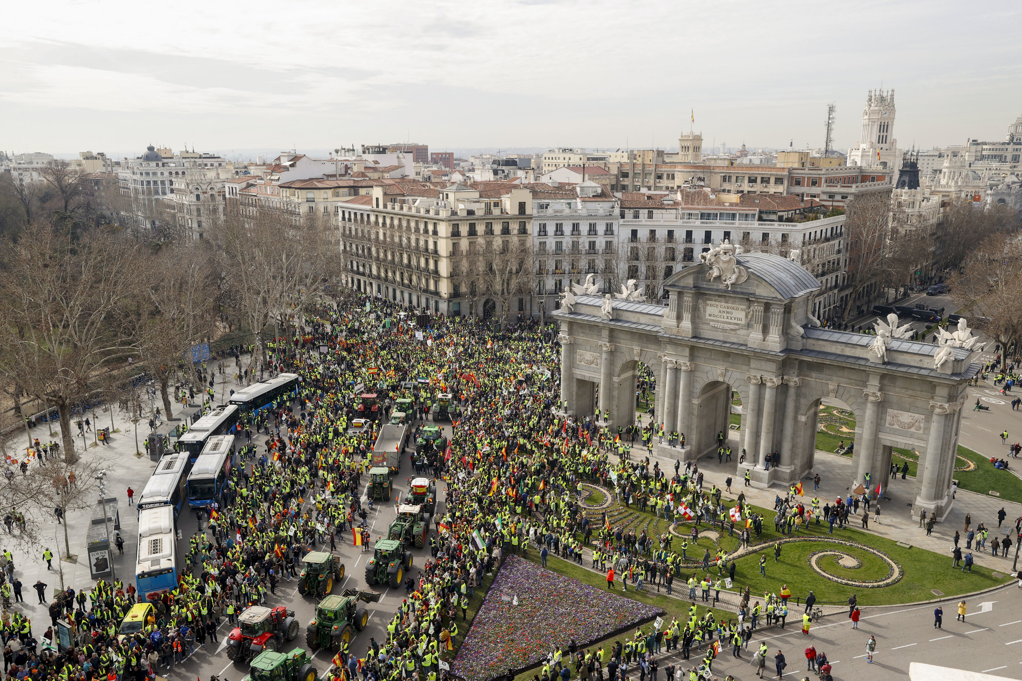Un numeroso grupo de manifestantes y de tractores a su paso por la Puerta de Alcalá con rumbo a la sede del Ministerio de Agricultura.