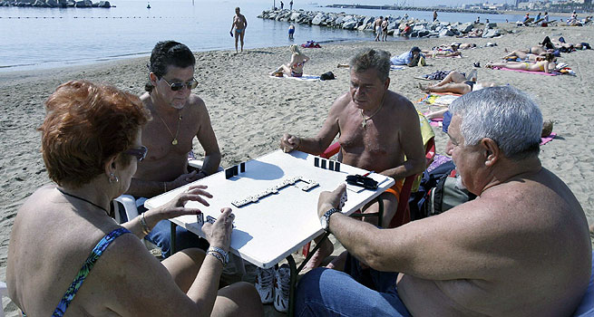 Un grupo de jubilados disfrutan del buen tiempo jugando al dominó en la playa de la Barceloneta. EFE/ Julián Martín.