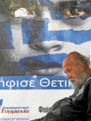 Un hombre, sentado ayer al lado de un anuncio del partido conservador Nueva Democracia en Atenas.